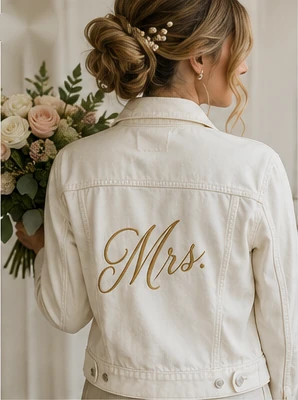 White denim jacket with gold script embroidery styled for a wedding.