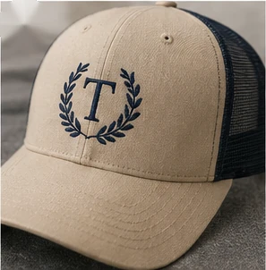Khaki and navy trucker cap with crest embroidery.