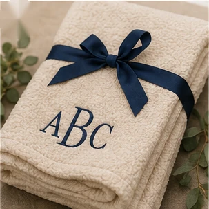 Cream blanket with navy monogram embroidery and ribbon.